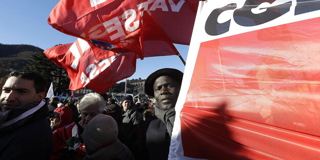 Rote Fahnen und ein Mann, der ein rotes Transparent hält, in einer Demo Rote Fahnen und ein Mann, der ein rotes Transparent hält, in einer Demo