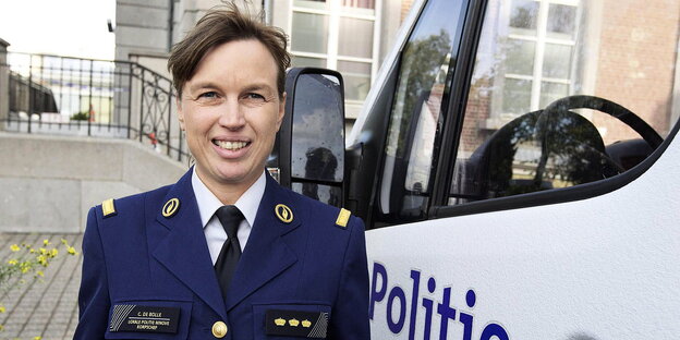 Eine Frau in Uniform neben der Fahrertür eines Polizeiautos Eine Frau in Uniform neben der Fahrertür eines Polizeiautos