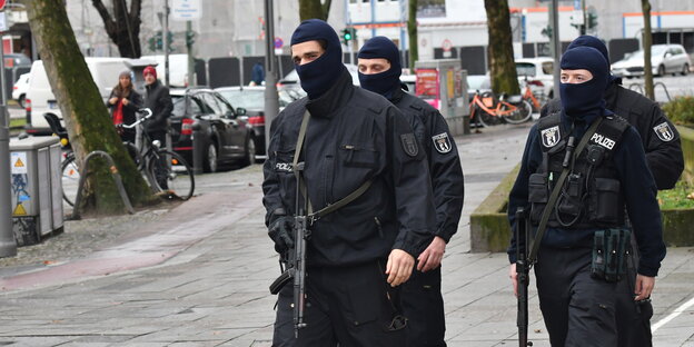 Drei vermummte Polizisten laufen über eine Straße Drei vermummte Polizisten laufen über eine Straße
