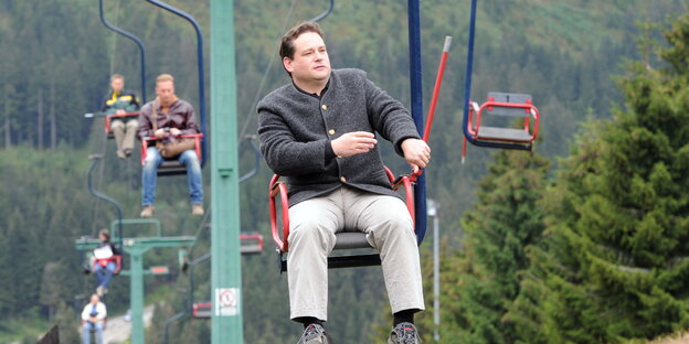 Alexander Bonde fährt mit einem Sessellift im Nordschwarzwald auf den Ruhestein