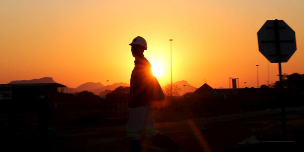 Die Silhouette eines Mannes vor einem Sonnenuntergang Die Silhouette eines Mannes vor einem Sonnenuntergang