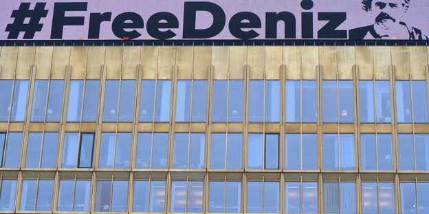 ein Hochhaus, über dem „#FreeDeniz “ steht