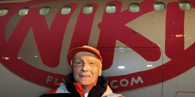 ein Mann steht neben einem Flugzeug, auf dem „Niki“ steht ein Mann steht neben einem Flugzeug, auf dem „Niki“ steht