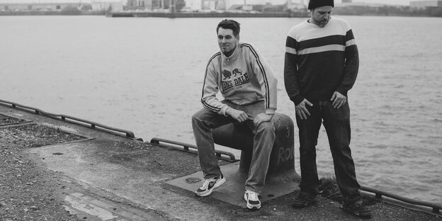 Zwei junge Männer sitzen am Hamburger Hafen, es sind die Rapper Johnny Mauser und Captain Gips Zwei junge Männer sitzen am Hamburger Hafen, es sind die Rapper Johnny Mauser und Captain Gips