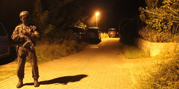 Ein Polizist im Dunkeln auf einer gepflasterten Weg, der von einer Laterne beleuchtet wird Ein Polizist im Dunkeln auf einer gepflasterten Weg, der von einer Laterne beleuchtet wird