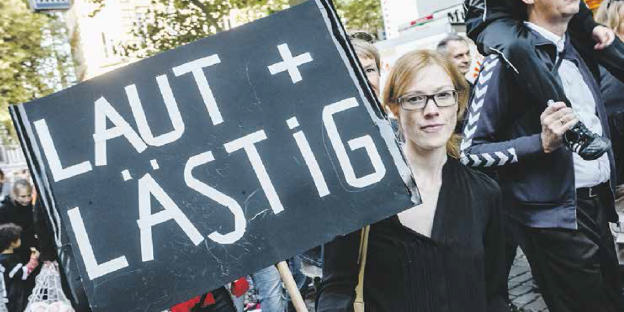 eine Frau hält ein Schild hoch, auf dem steht "Laut und Lästig" eine Frau hält ein Schild hoch, auf dem steht "Laut und Lästig"