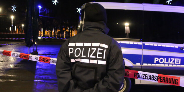 Ein Polizist steht vor einem Absperrband Ein Polizist steht vor einem Absperrband