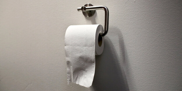Eine Rolle Toilettenpapier an einem Halter Eine Rolle Toilettenpapier an einem Halter
