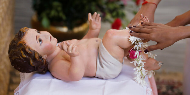 eine Babyfigur wird von Frauenhänden berührt eine Babyfigur wird von Frauenhänden berührt