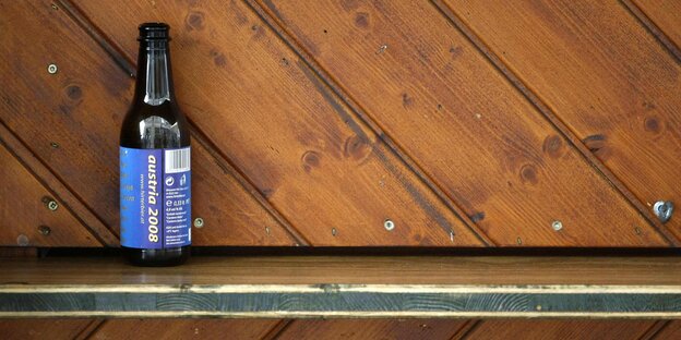 Eine leere Bierflasche auf einer Holztheke Eine leere Bierflasche auf einer Holztheke