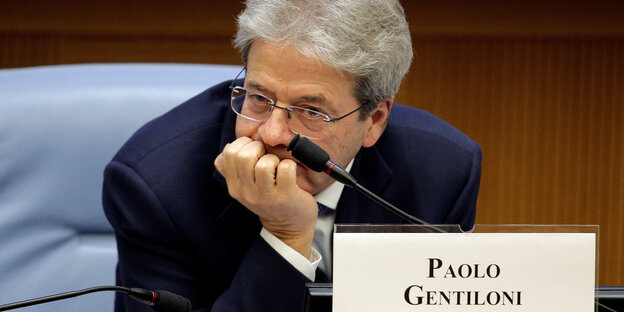 Paolo Gentiloni sitzt nach vorn gebeugt an einem Tisch Paolo Gentiloni sitzt nach vorn gebeugt an einem Tisch