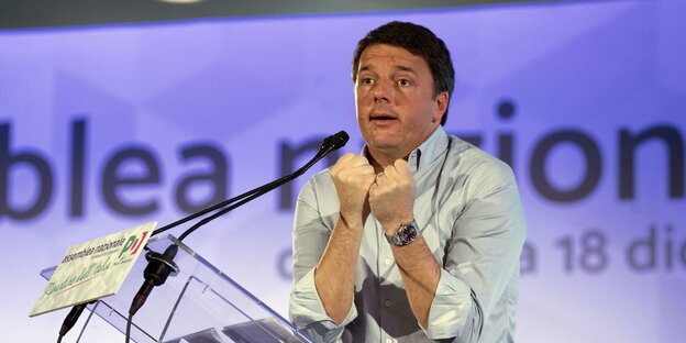 Matteo Renzi steht hinter einem Mikrofon und zieht seine geballte Fäuste an den Oberkörper Matteo Renzi steht hinter einem Mikrofon und zieht seine geballte Fäuste an den Oberkörper