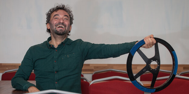 Fahrlehrer Süleyman Tuncel hält lachend ein Lenkrad Fahrlehrer Süleyman Tuncel hält lachend ein Lenkrad