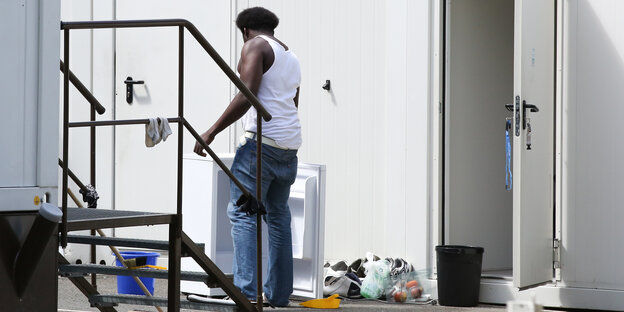 Mann steht vor einem Wohncontainer Mann steht vor einem Wohncontainer