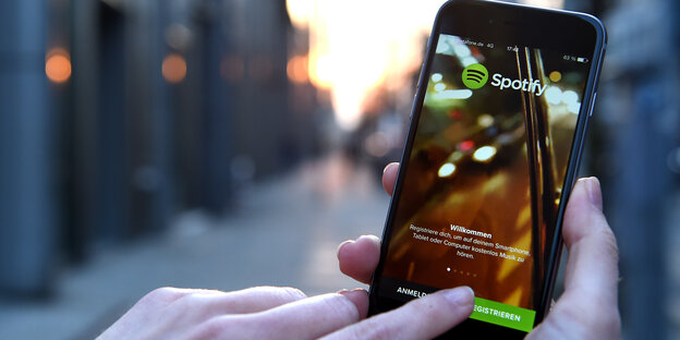 Jemand hält ein Smartphone in der Hand und tippt auf die Spotify-App Jemand hält ein Smartphone in der Hand und tippt auf die Spotify-App