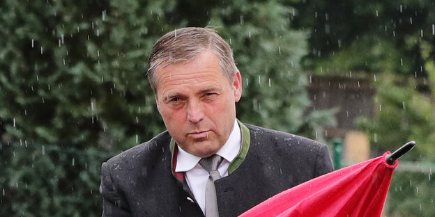 NPD-Politiker Udo Pastörs faltet einen Regenschirm zusammen. NPD-Politiker Udo Pastörs faltet einen Regenschirm zusammen.