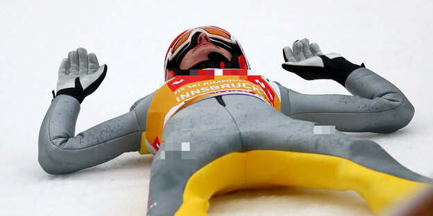 Ein Skispringer liegt auf dem Rücken im Schnee