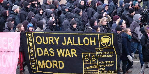 Ein Transpi „Oury Jalloh das war Mord“, dahinter schwarze gekleidete Menschen Ein Transpi „Oury Jalloh das war Mord“, dahinter schwarze gekleidete Menschen