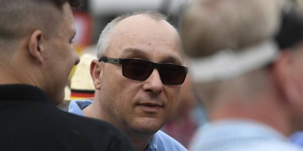 Ein Mann mit Sonnenbrille zwischen anderen Männern Ein Mann mit Sonnenbrille zwischen anderen Männern