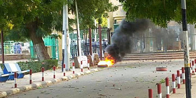 ein brennedes Objekt vor einem Eingangstor, dahinter uniformierte Polizei ein brennedes Objekt vor einem Eingangstor, dahinter uniformierte Polizei