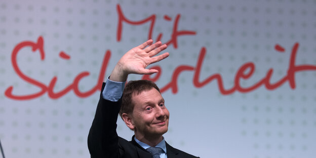 Sachsens Ministerpräsident Michael Kretschmer winkt fröhlich vor dem Schriftzug "Mit Sicherheit" Sachsens Ministerpräsident Michael Kretschmer winkt fröhlich vor dem Schriftzug "Mit Sicherheit"