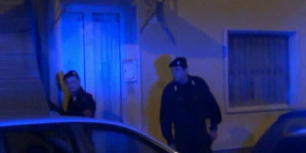 Zwei Carabinieri stehen im blauen Licht der Polizeisirenen vor einer verschlossenen Tür Zwei Carabinieri stehen im blauen Licht der Polizeisirenen vor einer verschlossenen Tür