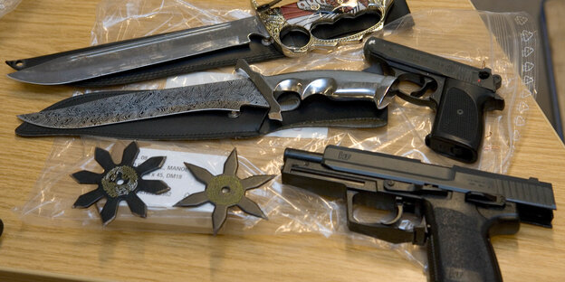 Zwei Messer, zwei Pistolen und zwei Wurfsterne liegen auf einem Tisch. Zwei Messer, zwei Pistolen und zwei Wurfsterne liegen auf einem Tisch.