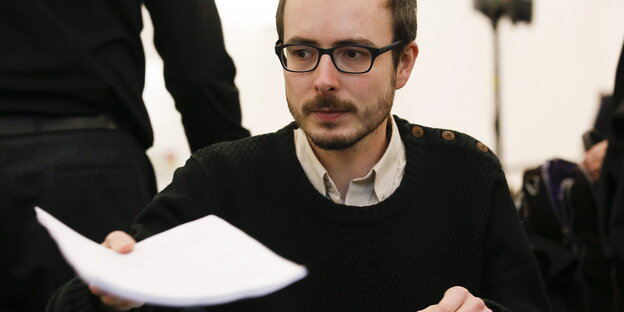 Ein Mann mit Brille hält ein Blatt Papier Ein Mann mit Brille hält ein Blatt Papier