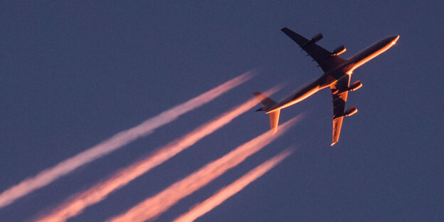 Im Licht der untergehenden Sonne zieht ein Flugzeug seine Kondensstreifen über den Himmel in Frankfurt am Main Im Licht der untergehenden Sonne zieht ein Flugzeug seine Kondensstreifen über den Himmel in Frankfurt am Main