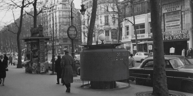 Schwarzweiß Foto des Boulevard des Capucines in Paris mit rundem Pissoir auf dem Trottoir. Schwarzweiß Foto des Boulevard des Capucines in Paris mit rundem Pissoir auf dem Trottoir.