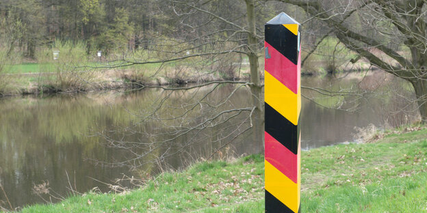 Am Ufer der Neiße steht ein Pfahl in den Symbolfarben Deutschlands Am Ufer der Neiße steht ein Pfahl in den Symbolfarben Deutschlands
