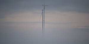 Windrad und Kran im Nebel