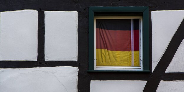 Eine Deutschlandfahne behängt ein Fenster in einem Fachwerkhaus Eine Deutschlandfahne behängt ein Fenster in einem Fachwerkhaus