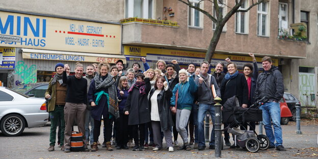 Die Mieterinnen und Mieter von AmMa65 stehen in einer Gruppe von etwa 30 Personen vor ihrem Haus, lachen, heben die Fäuste.