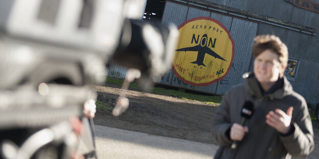 Ein Reporter am Flughafen von Notre-Dame-des-Landes, der Schriftzug „Nein zum flughafen“ im Hintergrund Ein Reporter am Flughafen von Notre-Dame-des-Landes, der Schriftzug „Nein zum flughafen“ im Hintergrund