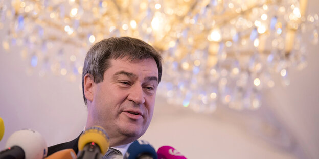 Markus Söder vor Mikros und unter einem großen Kronleuchter Markus Söder vor Mikros und unter einem großen Kronleuchter