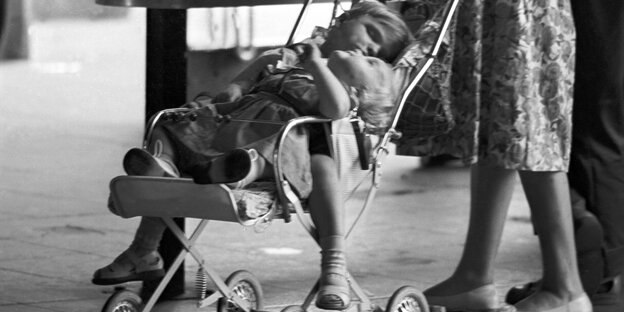 Schwarz-weiß-Foto von einer Mutter, die einen Kinderwagen schiebt Schwarz-weiß-Foto von einer Mutter, die einen Kinderwagen schiebt