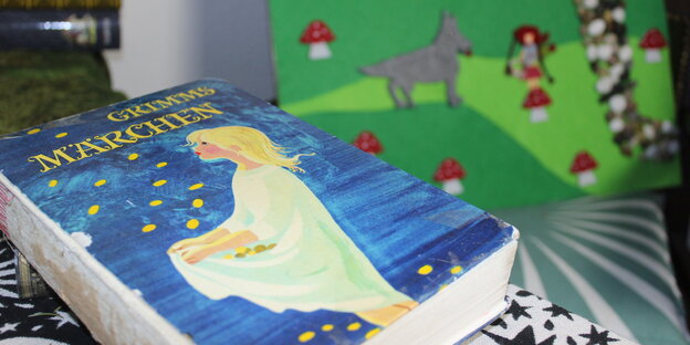Ein Buch auf einem Tisch. Auf dem Titelbild sieht man ein Mädchen, das Sterne, die herunter fallen mit seinem Kleid auffängt Ein Buch auf einem Tisch. Auf dem Titelbild sieht man ein Mädchen, das Sterne, die herunter fallen mit seinem Kleid auffängt