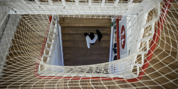 Ein Schüler geht eine Treppe hoch, deren Geländer mit einem Netz abgesichert ist. Ein Schüler geht eine Treppe hoch, deren Geländer mit einem Netz abgesichert ist.