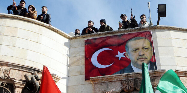 Ein Erdogan-Plakat an derFassade eines Hauses - auf dem Dach stehen Kämpfer mit Waffen Ein Erdogan-Plakat an derFassade eines Hauses - auf dem Dach stehen Kämpfer mit Waffen
