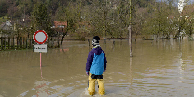 Ein Mensch in Anglerhosen steht im Hochwasser Ein Mensch in Anglerhosen steht im Hochwasser