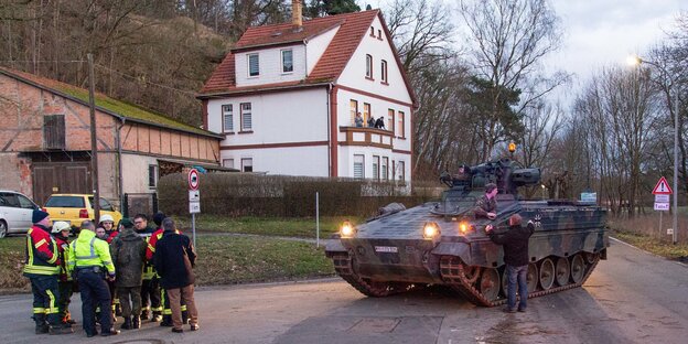 Ein Panzer steht vor einer Gruppe Feuerwehrleute Ein Panzer steht vor einer Gruppe Feuerwehrleute