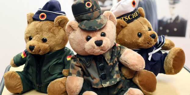 Drei Teddybären in Uniform sitzen nebeneinander Drei Teddybären in Uniform sitzen nebeneinander