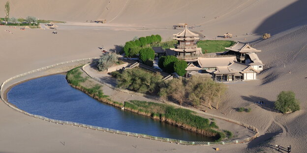 Häuser und Bäume an einem See umgeben von viel Sand Häuser und Bäume an einem See umgeben von viel Sand