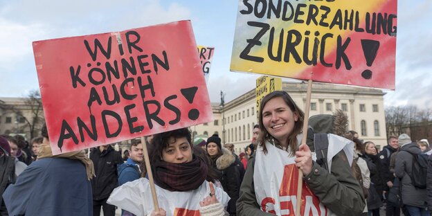 Zwei Frauen halten Schilder in die Höhe