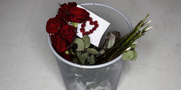 Rote Rosen in einem Abfalleimer Rote Rosen in einem Abfalleimer