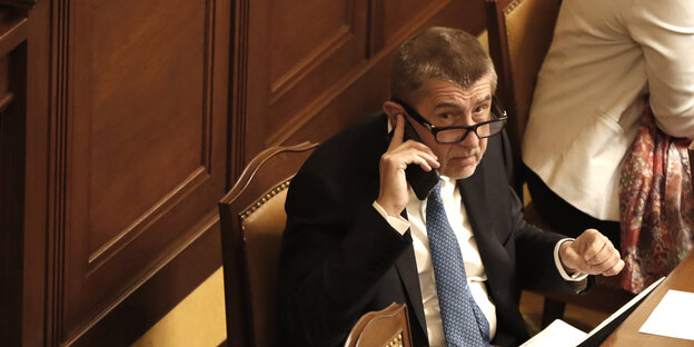 Andrej Babis sitzt an einem Tisch und hält ein Handy an sein Ohr Andrej Babis sitzt an einem Tisch und hält ein Handy an sein Ohr