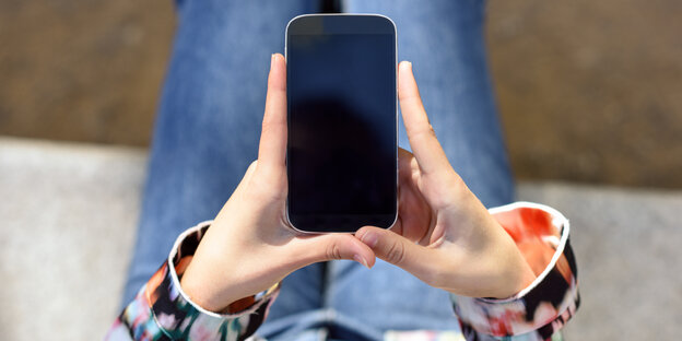 Eine Frau hält ein Smartphone in ihren Händen Eine Frau hält ein Smartphone in ihren Händen