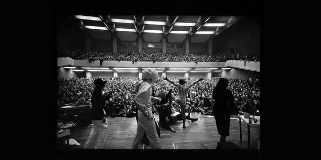 Schwarz-Weiß-Foto von einer Bühne in ein voll besetztes Auditorium Schwarz-Weiß-Foto von einer Bühne in ein voll besetztes Auditorium