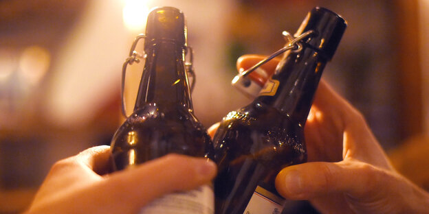 Zwei Personen stoßen mit Bierflaschen an Zwei Personen stoßen mit Bierflaschen an